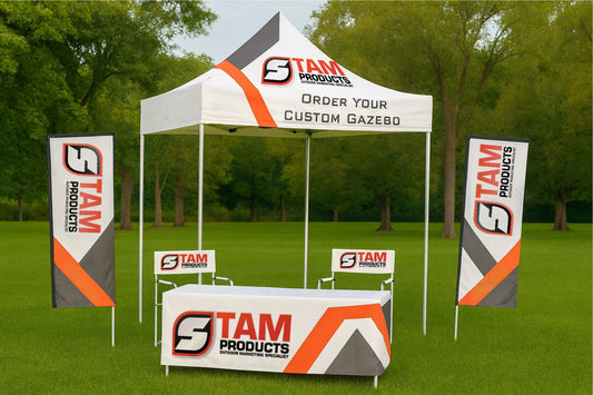 Bespoke branded mini gazebo with Stam Products logo, tablecloth, chairs, and flags in outdoor park setting