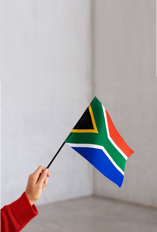 Hand holding a custom printed South African flag on a small black pole against a plain background