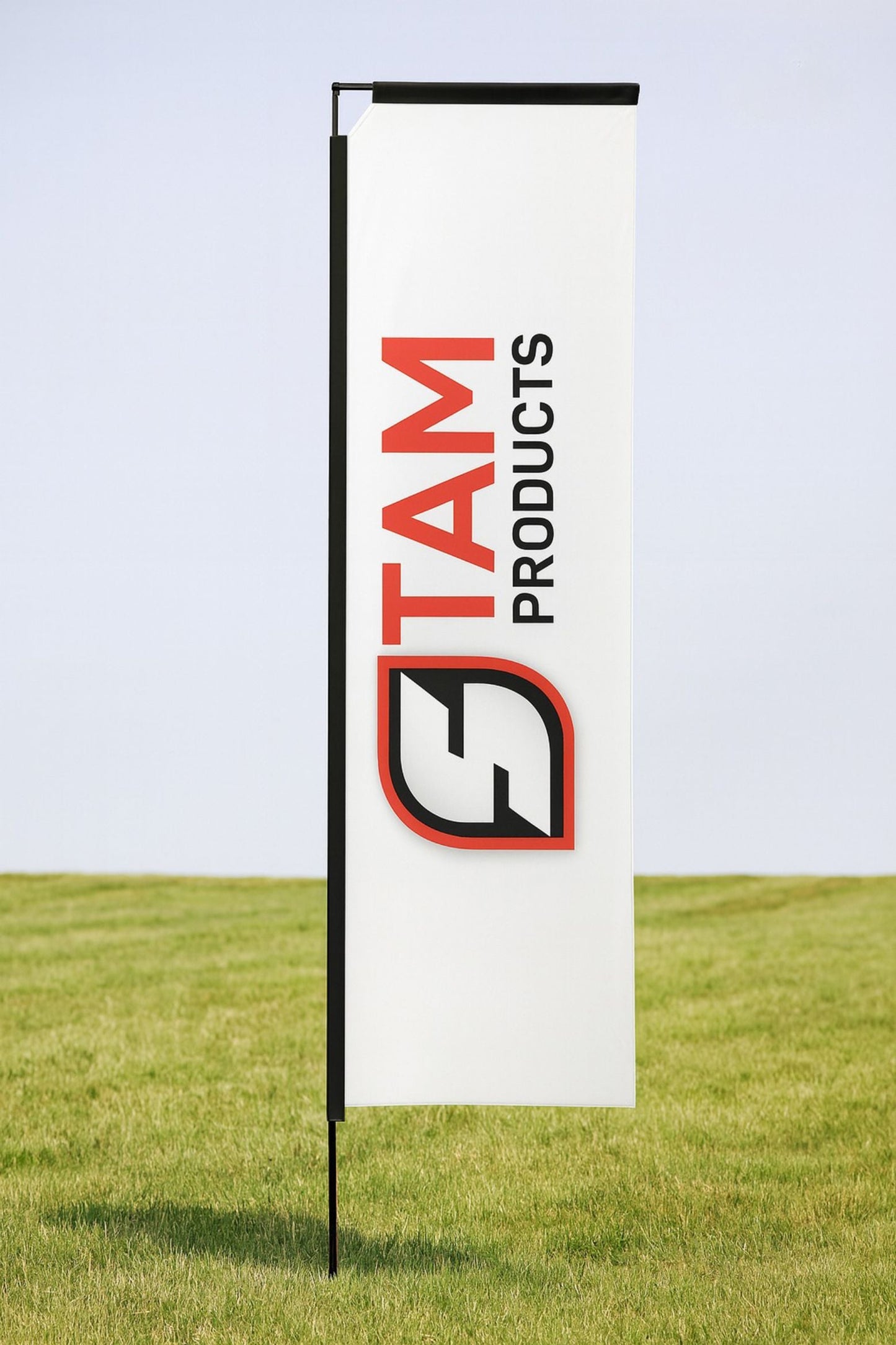 White telescopic flag banner with Stam Products logo in red and black on a grassy outdoor background