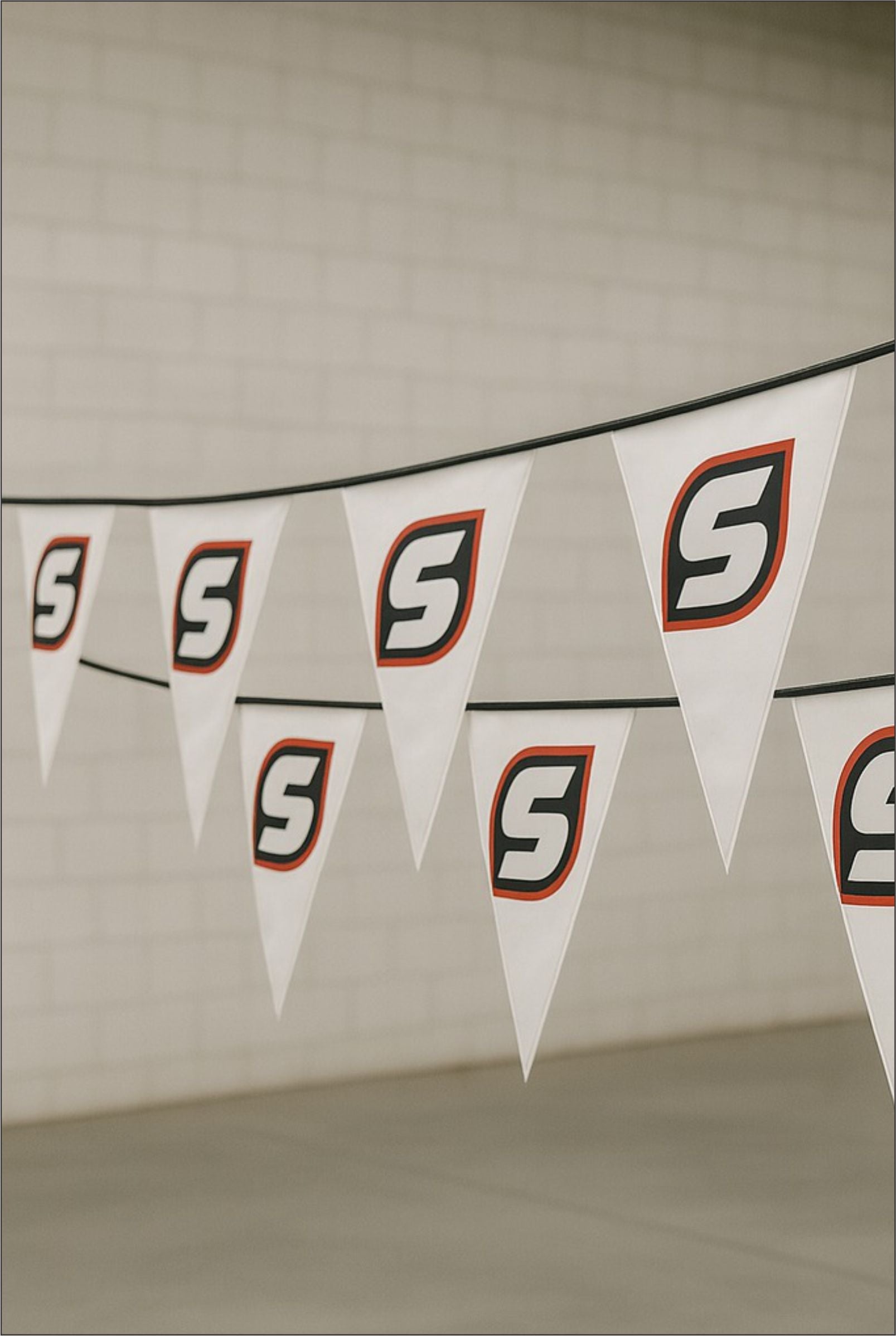 Custom printed white PVC bunting with Stam Products branded logo on triangular flags hanging indoors
